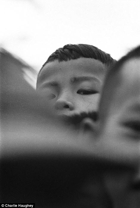 Curious: A local boy peeks over the heads of his friends to have a look at Mr Haughey's camera