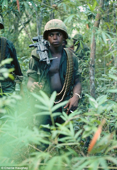 On the march: A machine gun operator walking through the jungle weighed down with guns and ammunition