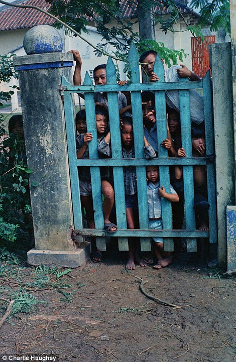 Locals: Vietnamese children peer through a gate at the American photographer during his tour in 1968-9